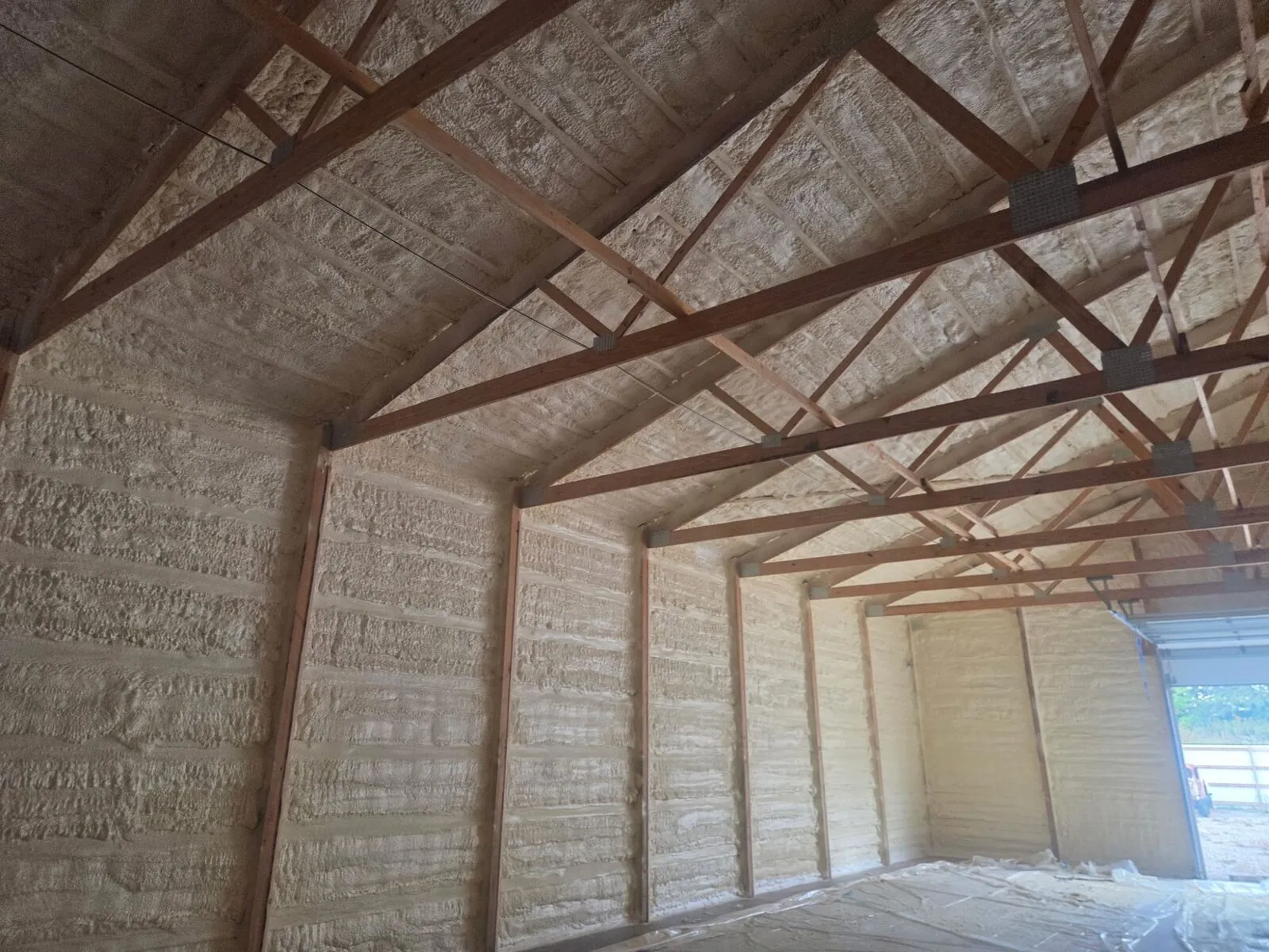 Spray foam insulation on shop sidewalls and ceiling between wood trusses